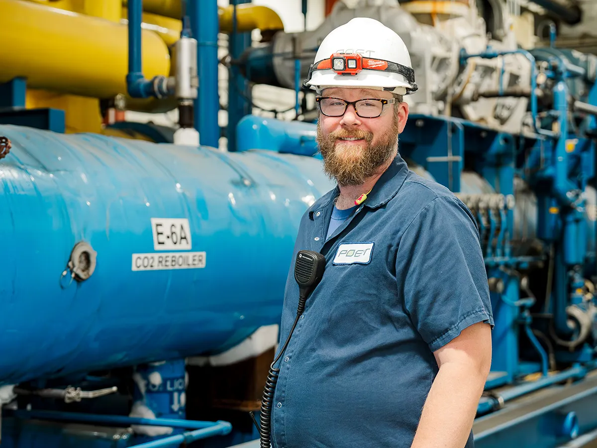 Hanson wearing a hard hat standing by a machine