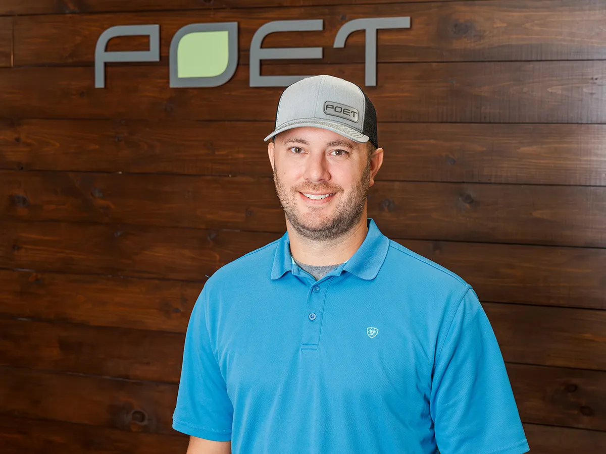 Pete standing by the wall with POET logo on the wall