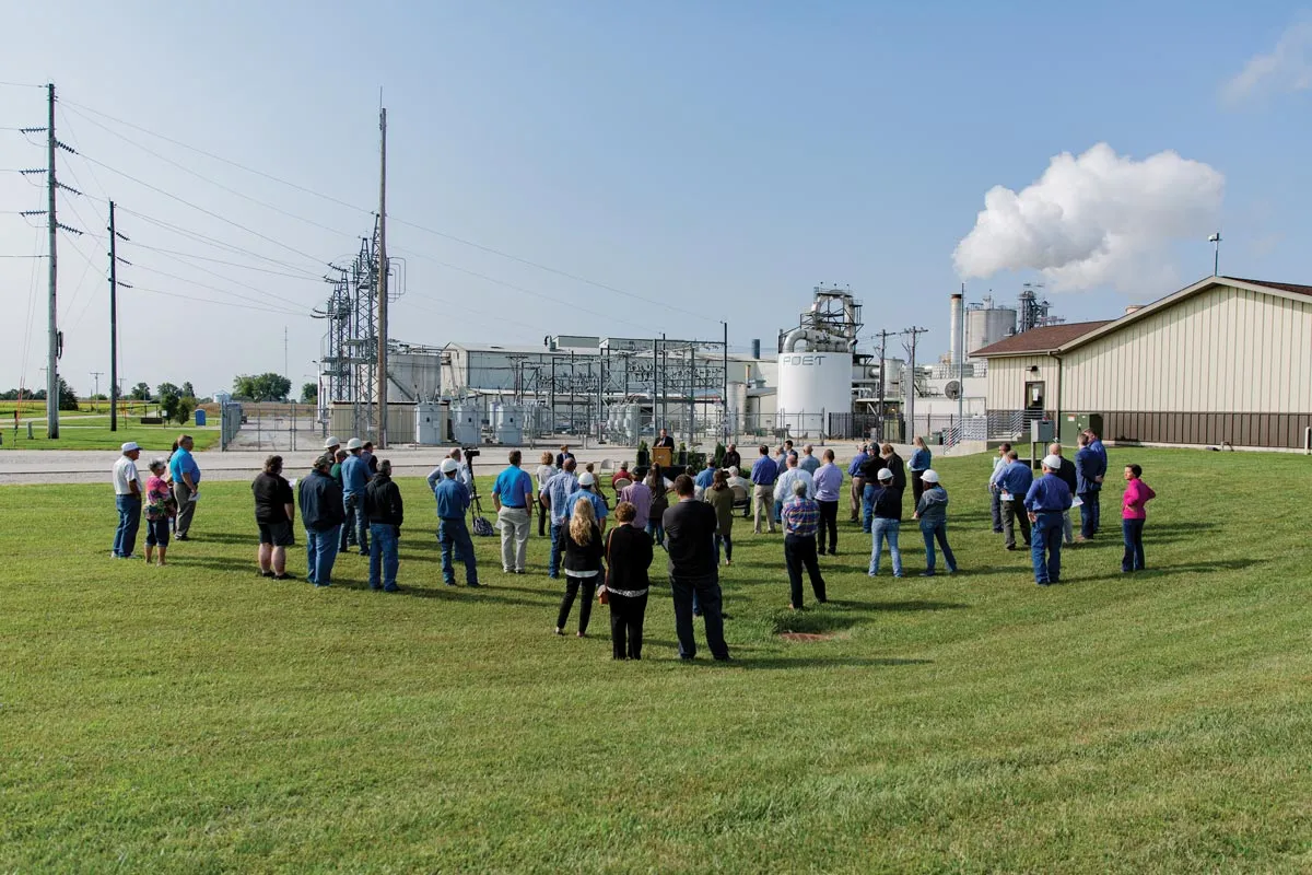 A group of people standing outside listening to a speech 