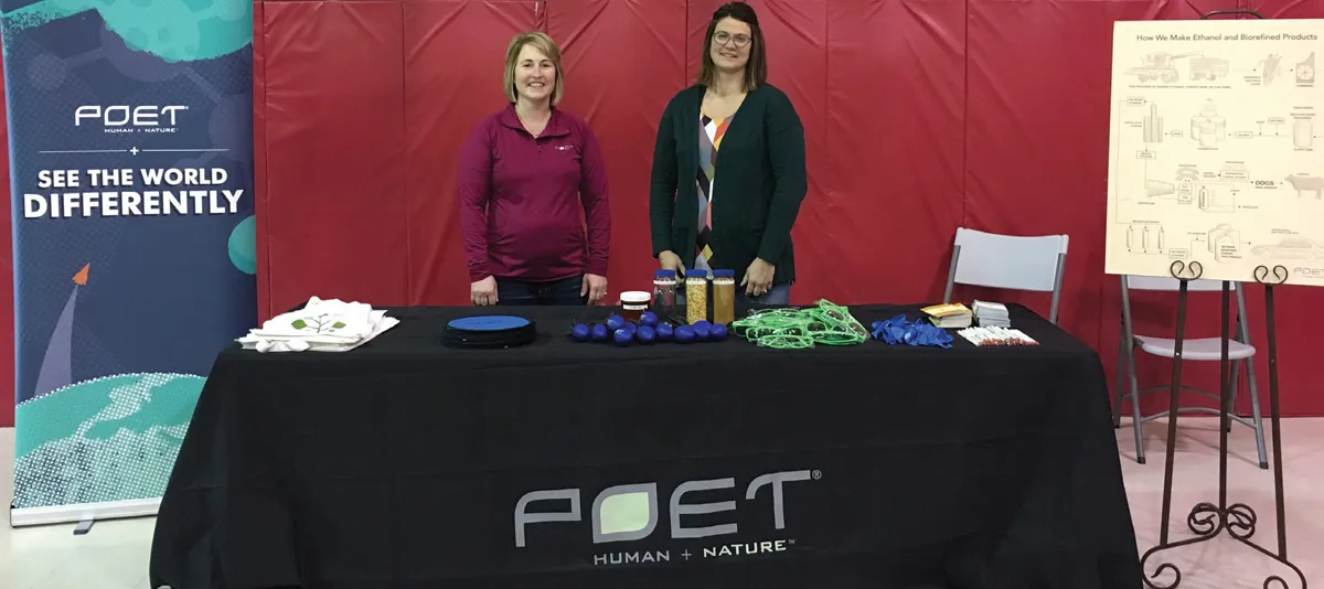 Two women at a POET booth behind a table