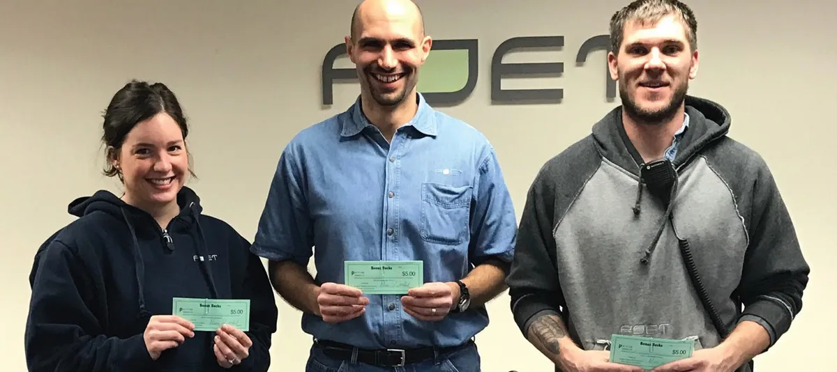 Three people holding prize checks and smiling