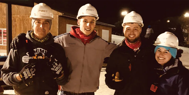 Four people wearing hard hats taking a picture outside