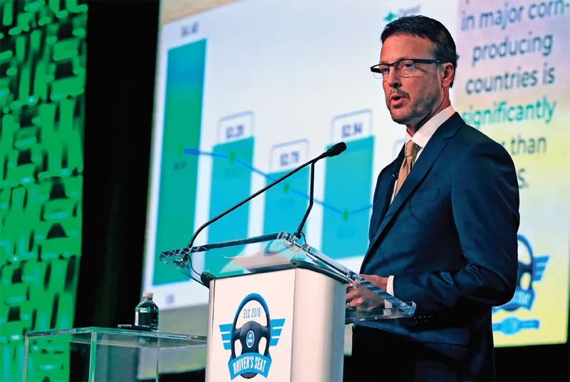 Man in suit speaks at podium on stage