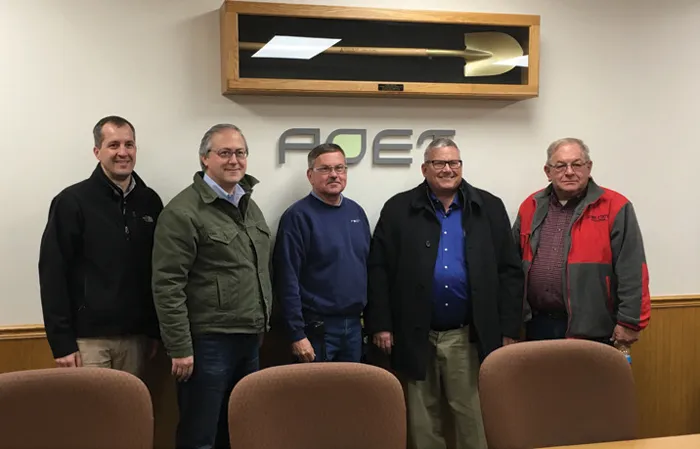 Five men taking a picture in front of POET logo on the wall