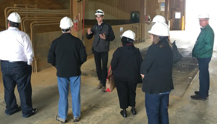 A tour guide addressing group in hard hats