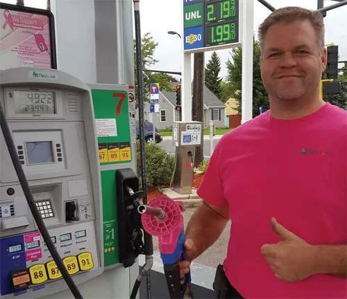 A man at a gas station showing thumb up