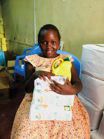 A primary school student in Nairobi smiles after receiving a food packet through Light Up Hope.