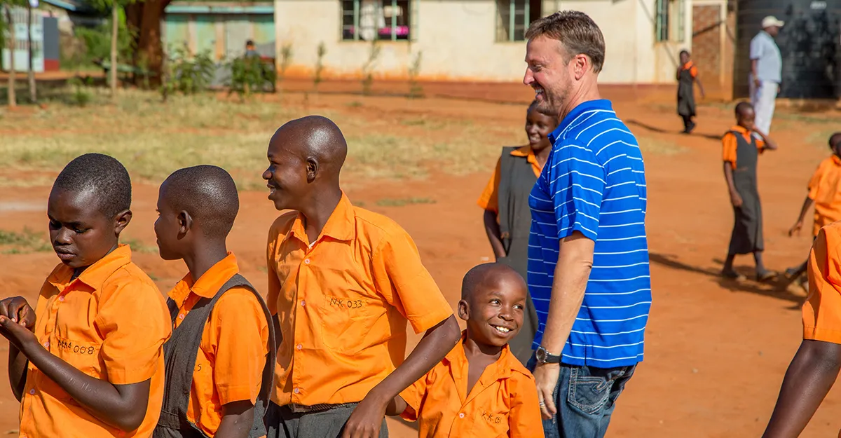 Man in blue striped shirt with orange-clad kids