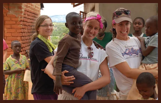 Smiling volunteers with children in village
