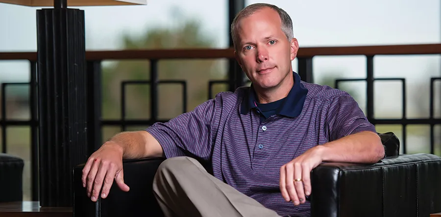 Bob in purple polo sits on black leather chair