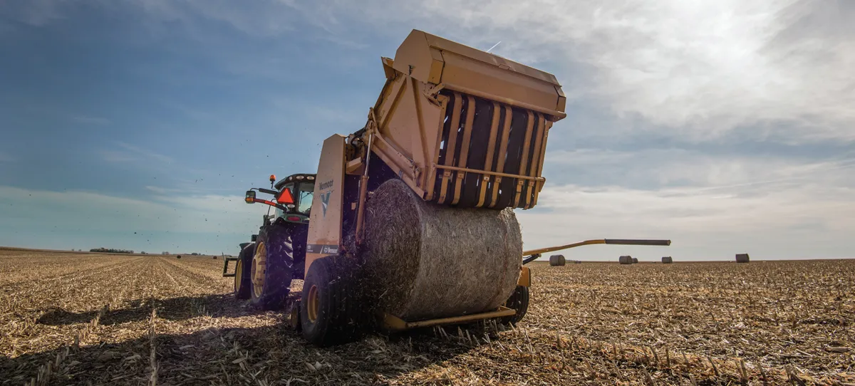 Tractor pulling bale-wrapping machine on field