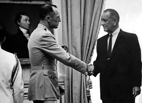 Uniformed officer shakes hands with suited man