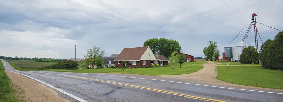Rural farmstead with house, silos, and road