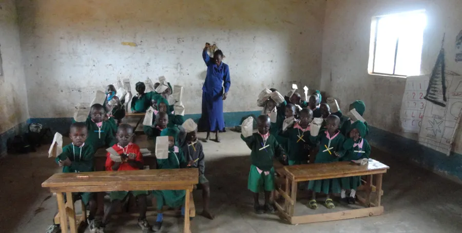 Students in green uniforms hold paper bags