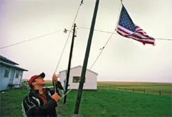Man raises American flag near flagpole