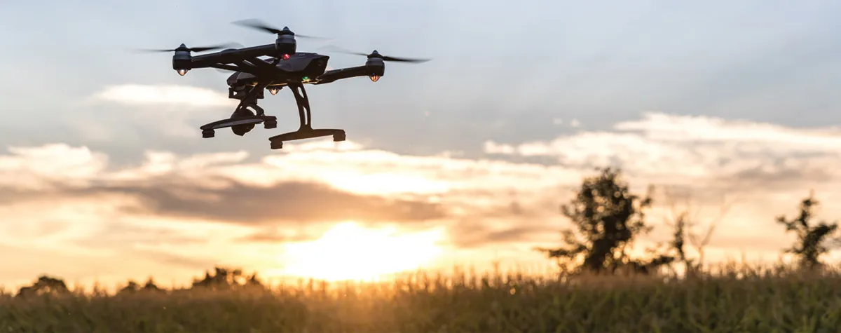 Drone flying over sunlit field at sunset