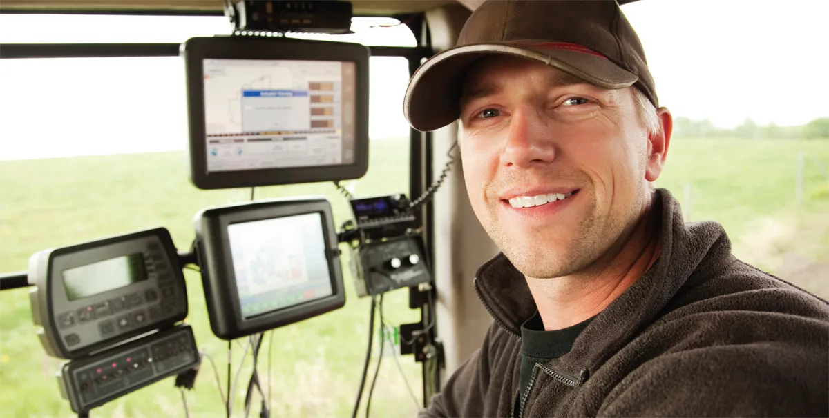 Smiling farmer in tractor cabin with screens