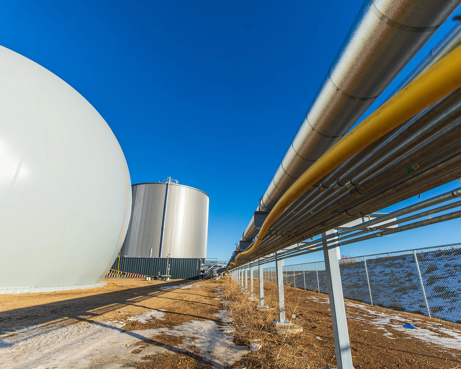Large white spherical tank and industrial piping