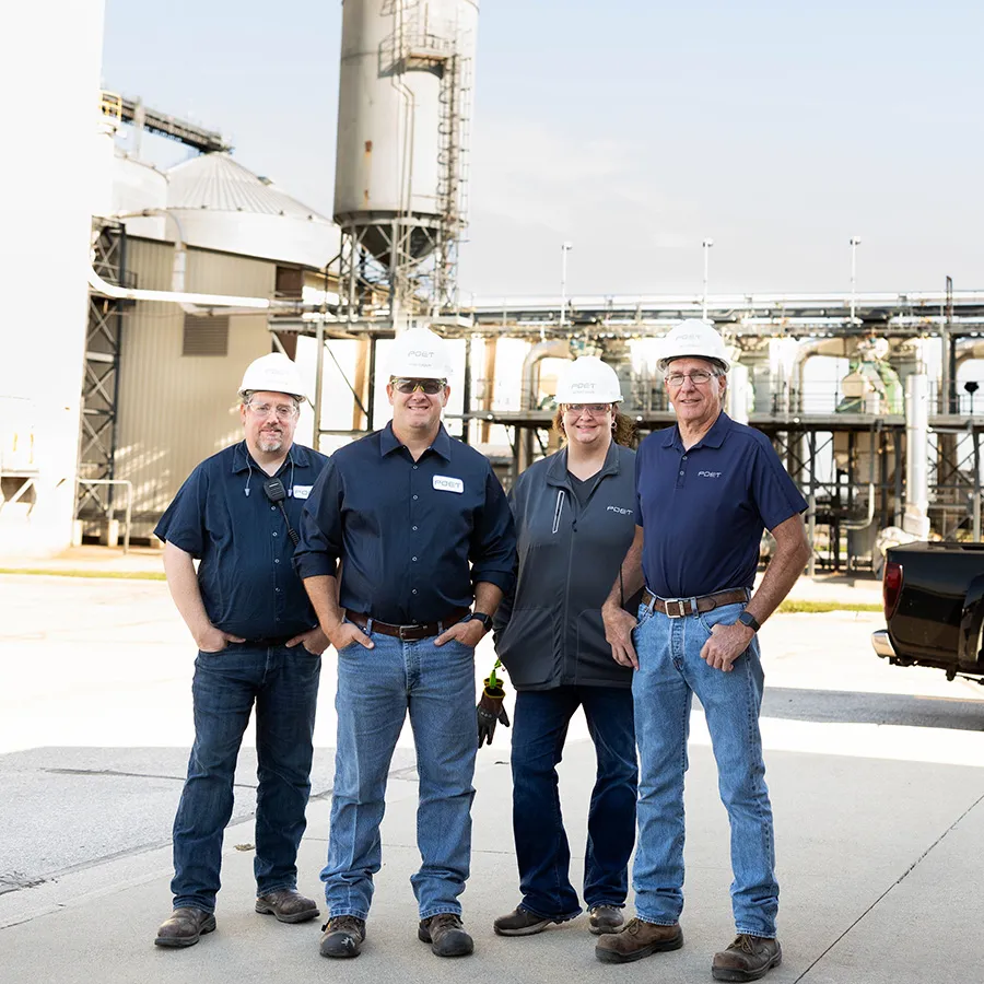 Four workers in hard hats at an industrial site