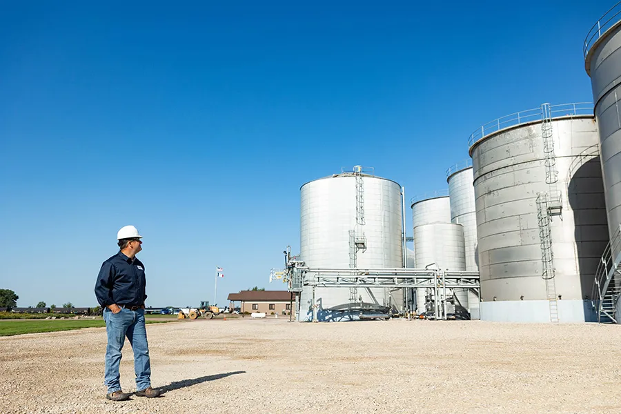Construction worker stands near metal silos