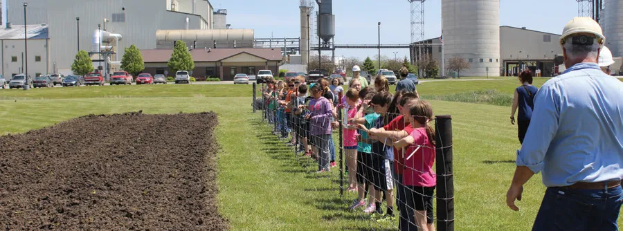 Children line the fence along the field