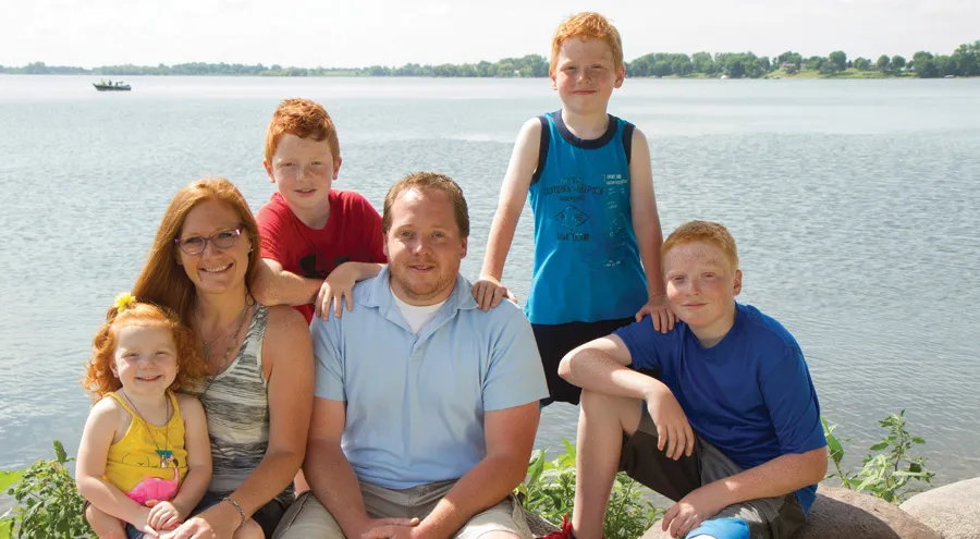 Family of six poses by a lake