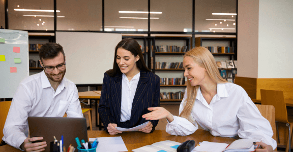 A group of people sitting around a table with a laptop.