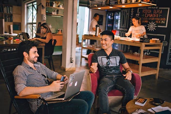Two men sitting in a cafe, one of them holding a laptop. - UserVoice Images