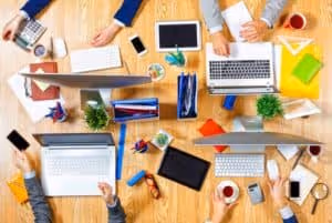 A wooden table with a laptop and a cell phone on it. - UserVoice Images
