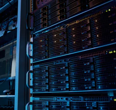 Close-up view of black server rack with multiple hard drives and blinking indicator lights in a data center.