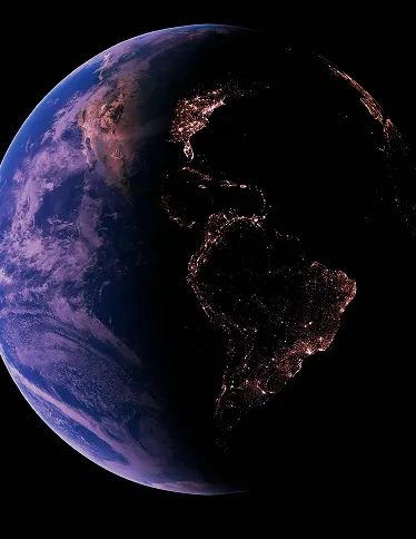 View of Earth from space showing the Americas with city lights visible on the night side and the day side partly illuminated.