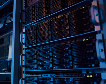 Close-up of multiple stacked black server racks with blinking lights in a data center.