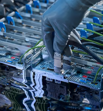 Hand wearing glove connects a cable to a submerged electronic circuit board in a liquid tank.
