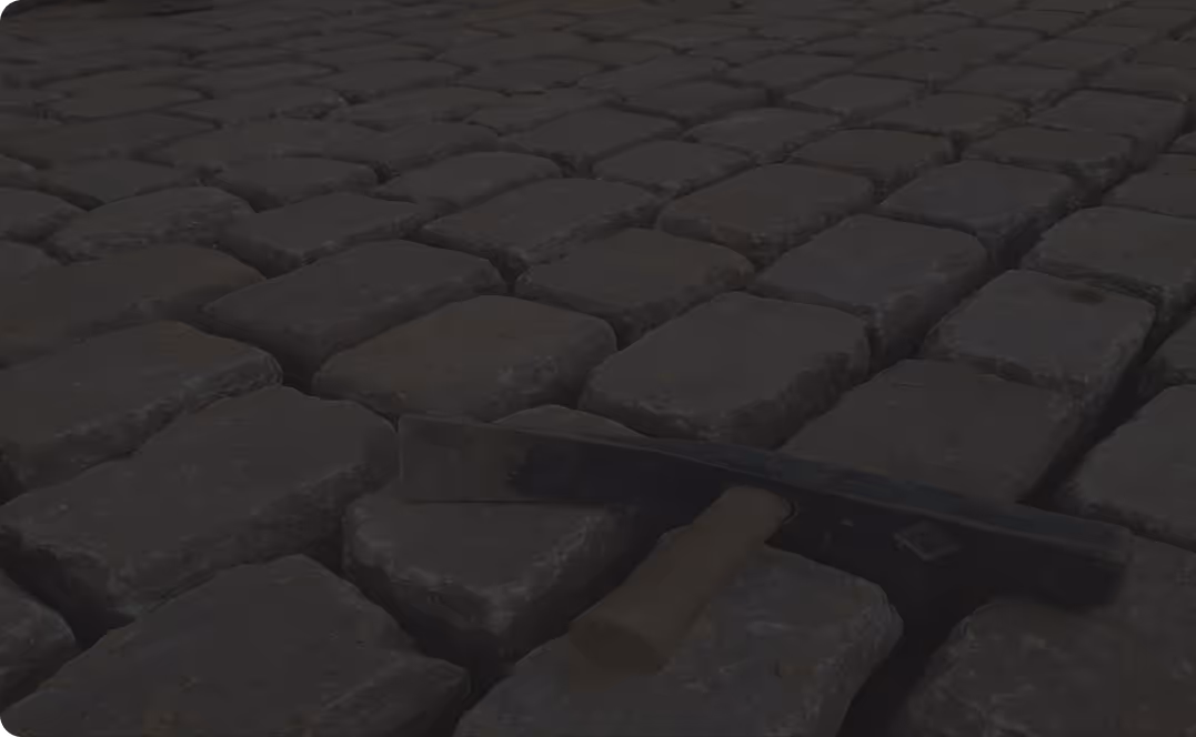 Ein Steinrechen liegt auf einem gepflasterten Weg aus rechteckigen Grausteinen.