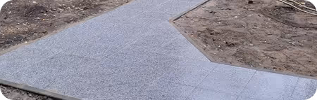 Hellgrauer Gehweg aus Pflastersteinen, der sich in einem Y-förmigen Muster verzweigt, umgeben von unebenem, braunem, unbepflanztem Boden.