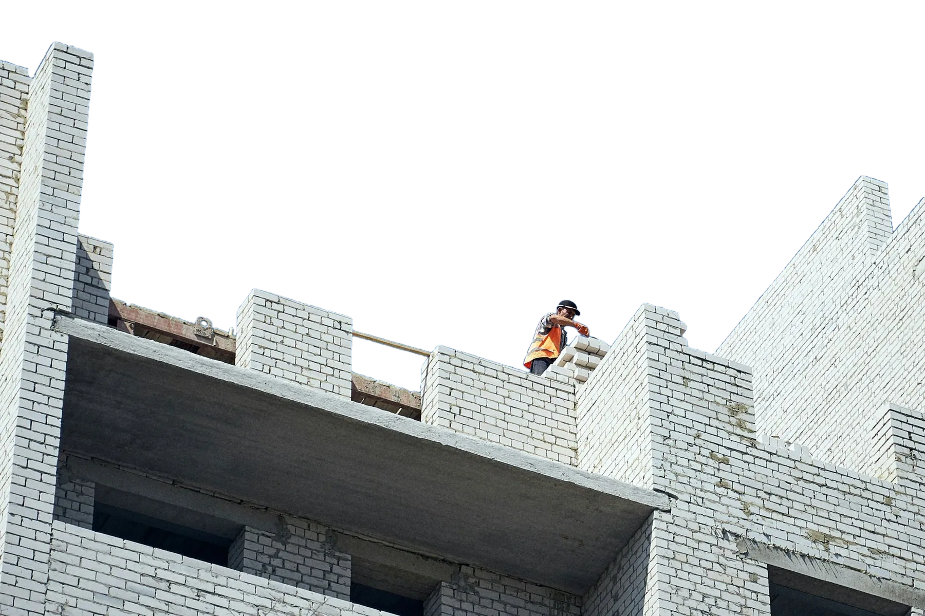 A bricklayer in orange hi-vis laying brick at roof level