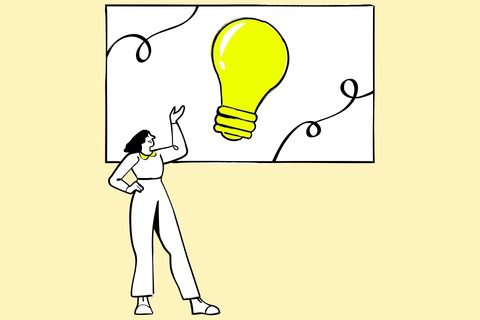 Donna in piedi con abbigliamento bianco guarda verso una grande lampadina gialla illuminata su uno schermo alle sue spalle.