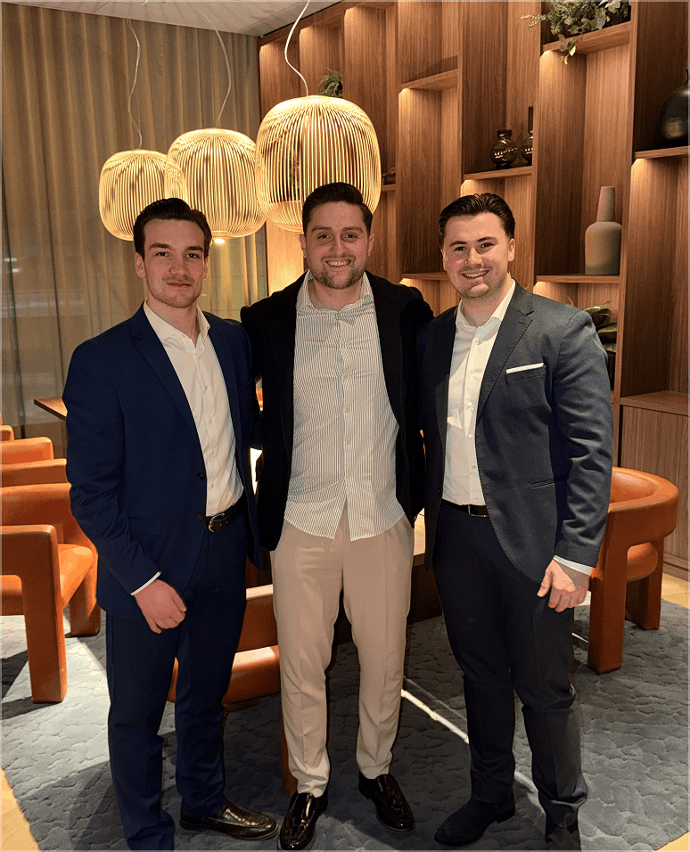 Drei Teammitglieder bei einem Business-Event am Abend, formelle Kleidung, professionelle Atmosphäre.