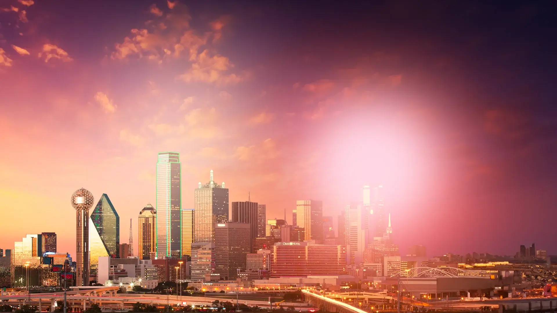 Dallas city skyline at sunset with glowing orange and pink clouds and illuminated buildings.