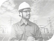 Engineer wearing a white hard hat and safety glasses reviewing notes with solar panels and electricity pylons in the background.