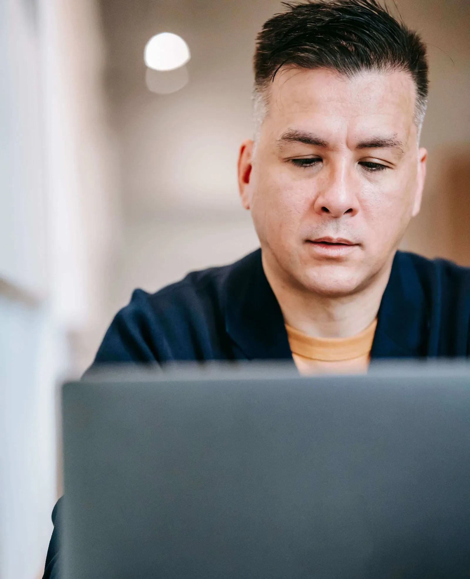 A man in a navy jacket working on a laptop