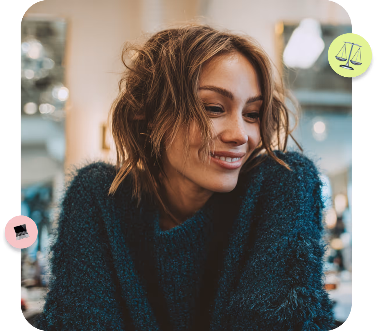 Smiling woman with tousled hair wearing a dark teal fuzzy sweater, indoor background.