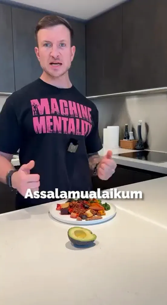 Man standing in kitchen with healthy meal and greeting text on screen.
