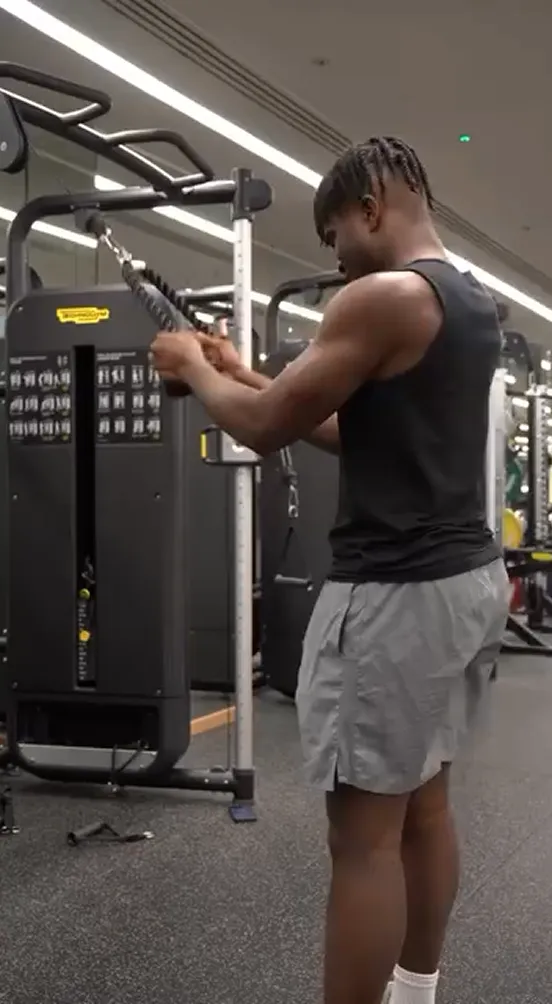Man performing cable triceps pushdowns in a gym.