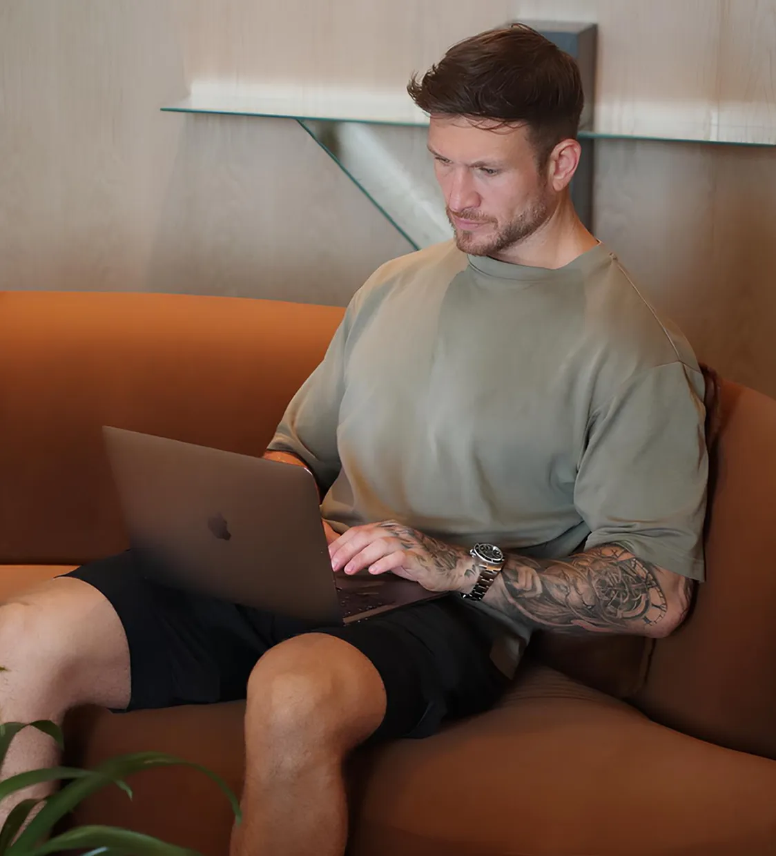Man sitting on a couch working on a laptop.