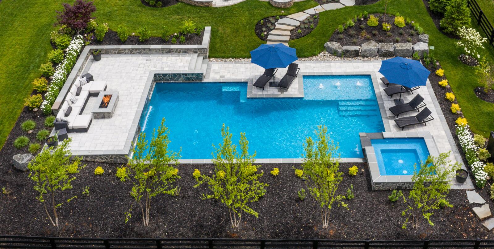 custom luxury pool with hot tub stone accents and fireplace lounge area in Northern Virginia