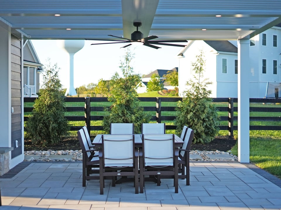 Covered paver patio with dining table and fan by Deckscapes of Virginia
