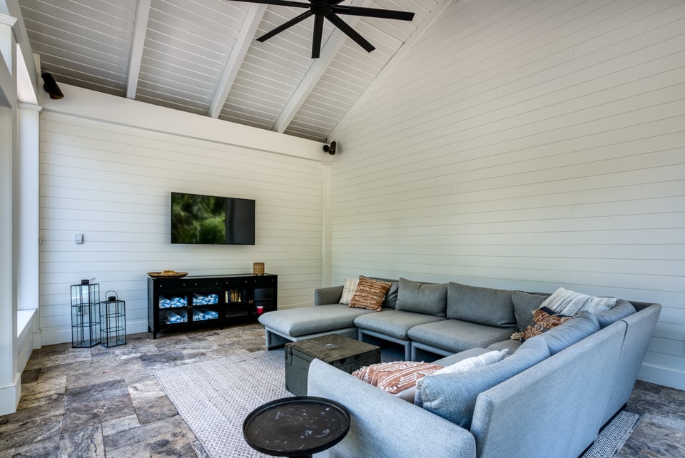 coverd patio with cozy living room, heaters, tv, and ceiling fan