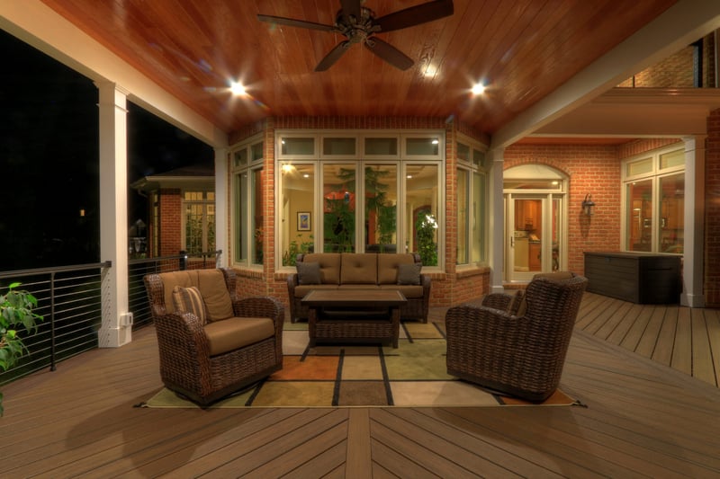 Custom deck with white posts and recessed lighting with view of windows to interior of home