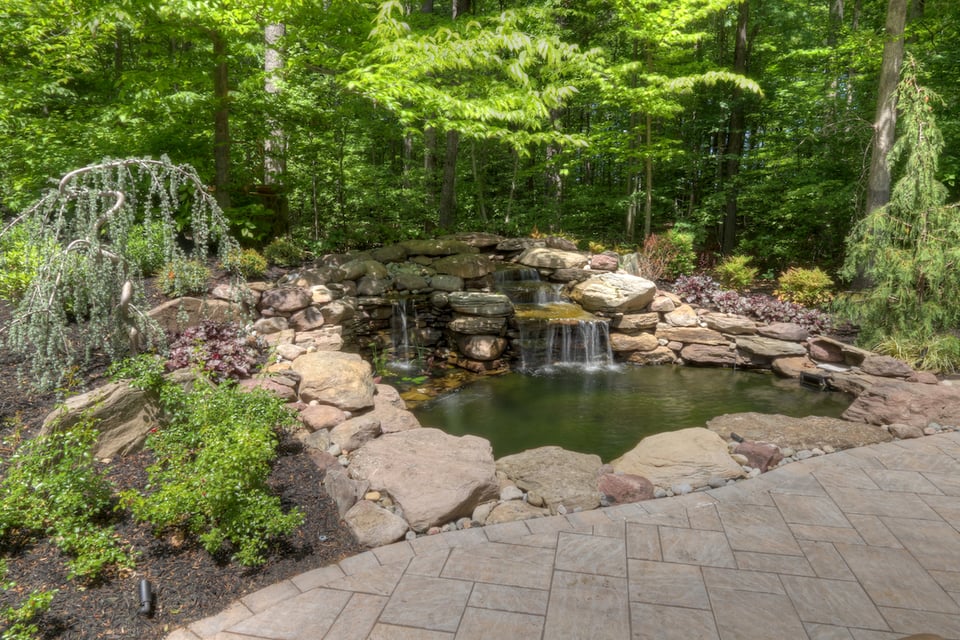 rock and water feature next to a paver patio in Northern Virginia by Deckscapes
